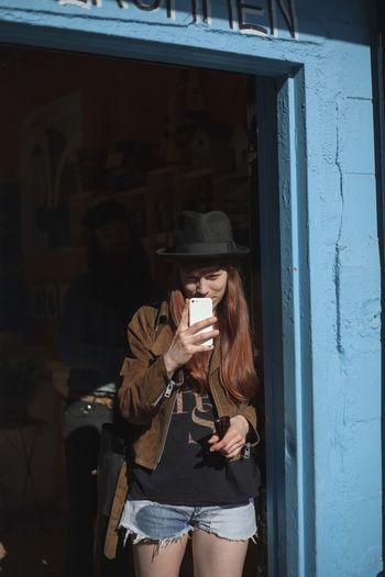 Woman holding mobile phone while standing at home