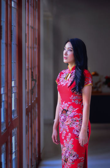 Young woman looking away while standing outdoors