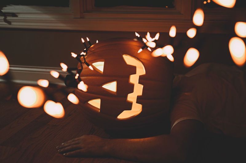 Man with jack o lantern and lighting equipment resting at home during halloween