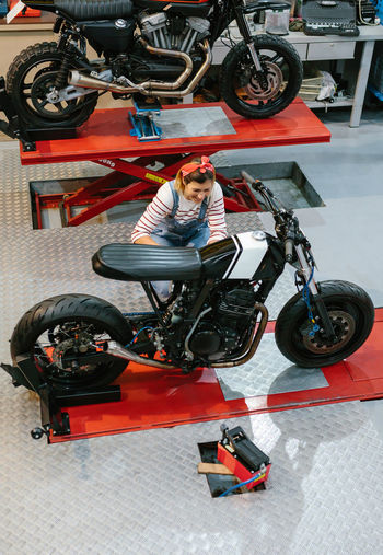 Mechanic woman reviewing custom motorcycle on factory