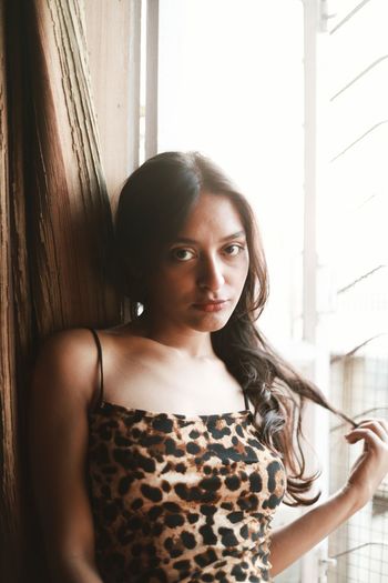 Portrait of young woman sitting on window