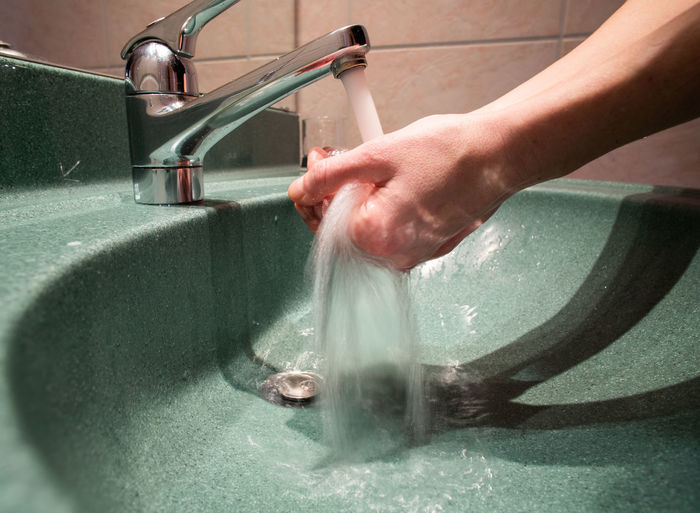Cropped image of woman washing hands in bathroom at home