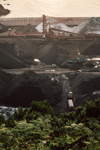 Aerial view of modern loader transporting cargo along coal mining stock in daylight