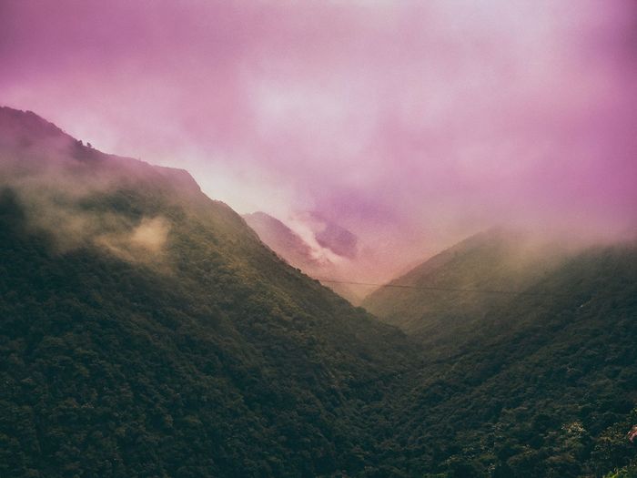 Scenic view of foggy mountains against sky during sunset