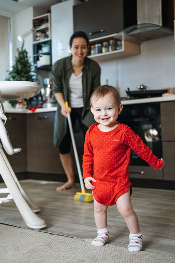 Little mothers helper. cute toddler baby girl with mop help her mom do housework in kitchen. cute
