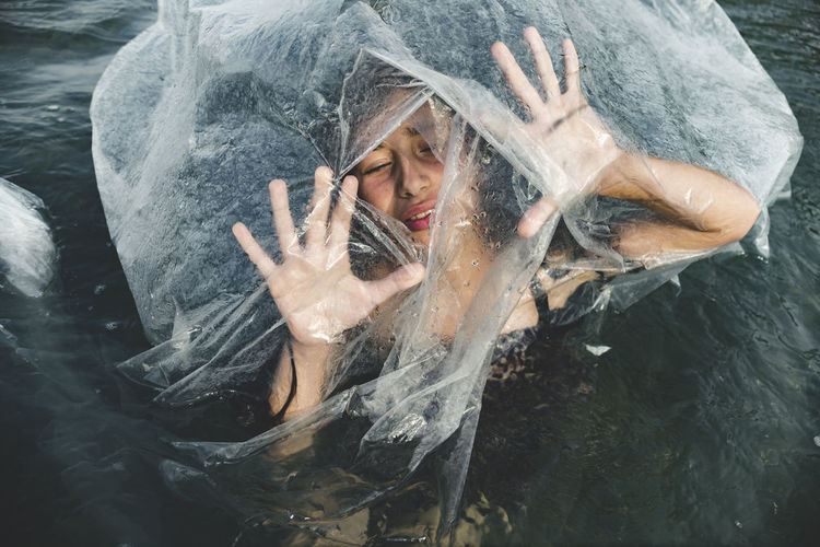High angle view of girl amidst plastic in sea