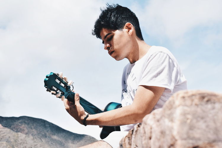 Man playing guitar against sky
