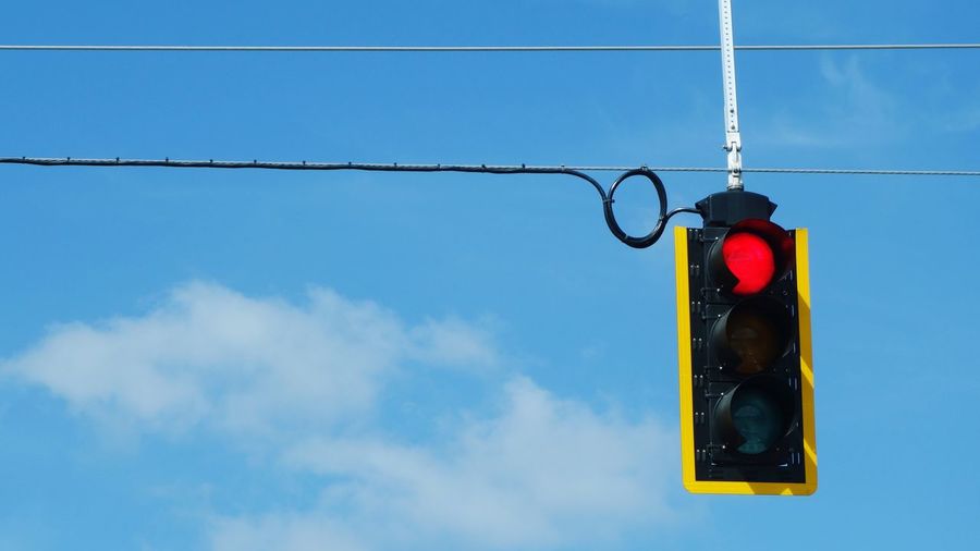 Low angle view of road signal against blue sky