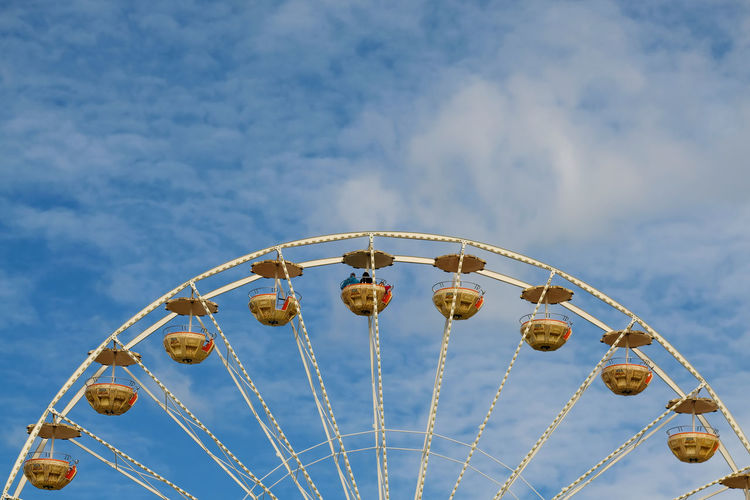 Low angle view of ferris wheel against blue sky during sunny day