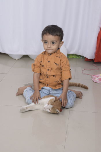 Boy sitting on cat at home