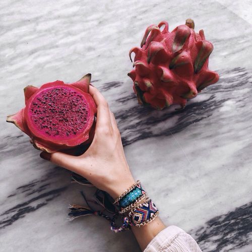 Cropped image of woman holding halved pitaya on table