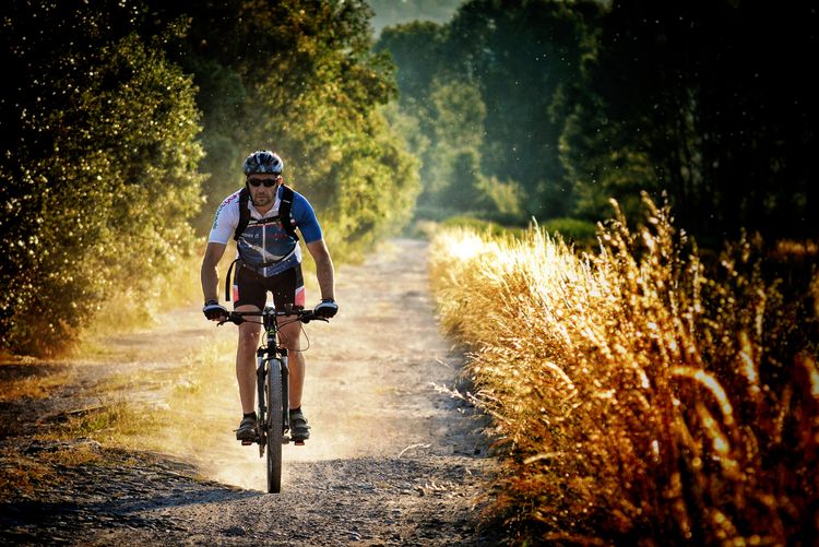 Young man riding bicycle on dirt road