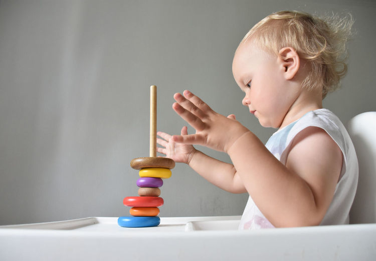 Side view of 23 months old girl playing with toy pyramid 