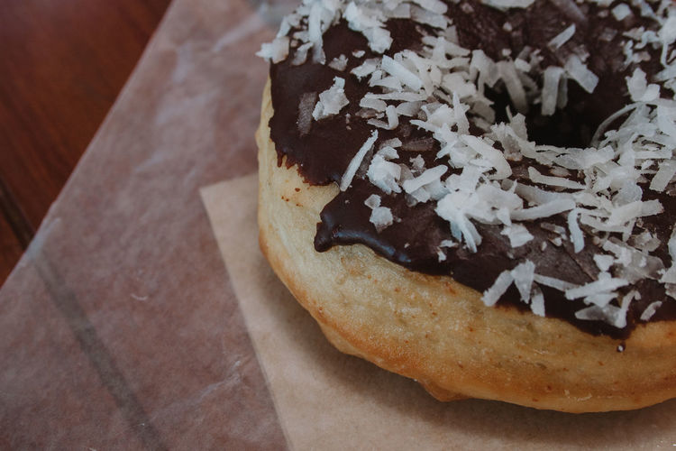 Close-up of chocolate donut with grated coconut at table