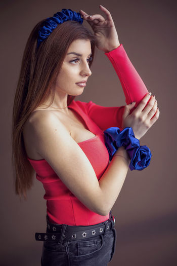 Young woman with arms crossed standing against wall