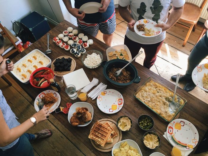 People standing in front of table having food at home