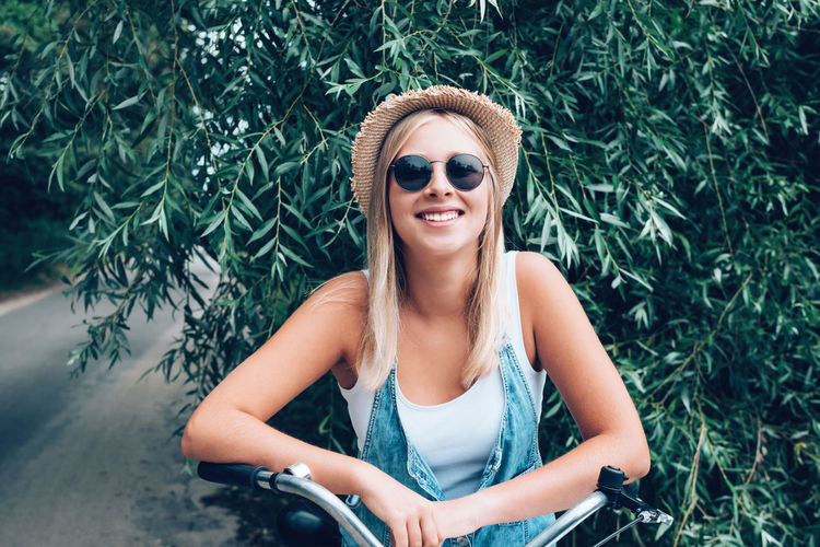 Beautiful young woman wearing sunglasses sitting outdoors