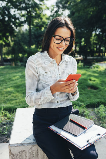 Portrait of young woman using laptop while sitting outdoors