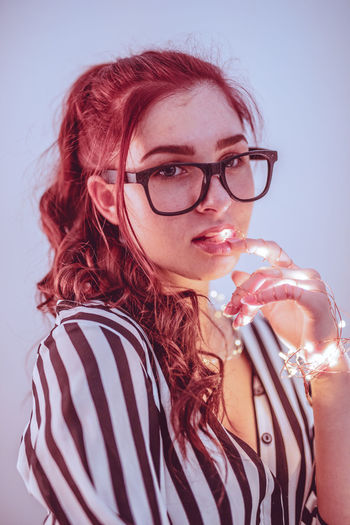 Young woman with illuminated string light against blue background