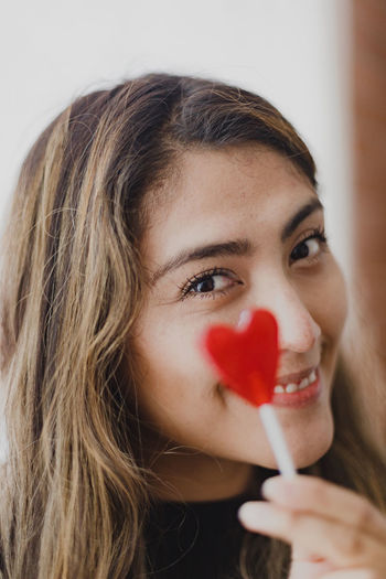 Latin woman in love with a lollipop in her hand in the shape of a heart. valentine's day