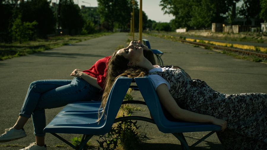 Side view of women relaxing at bench on road