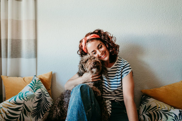 Portrait of happy woman with dog on sofa at home