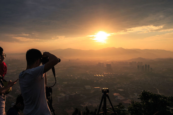 Man photographing sunset over landscape