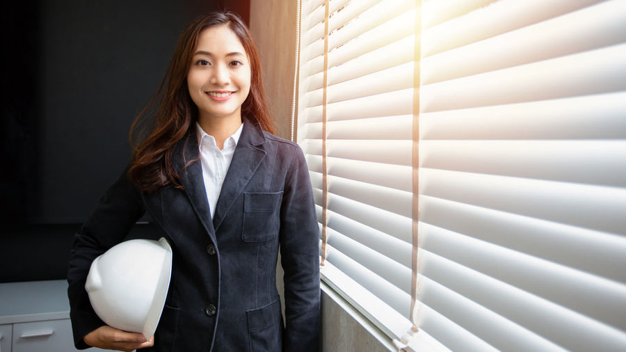 Portrait of businesswoman standing against window