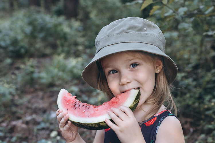 Portrait of cute girl eating watermelon outdoors