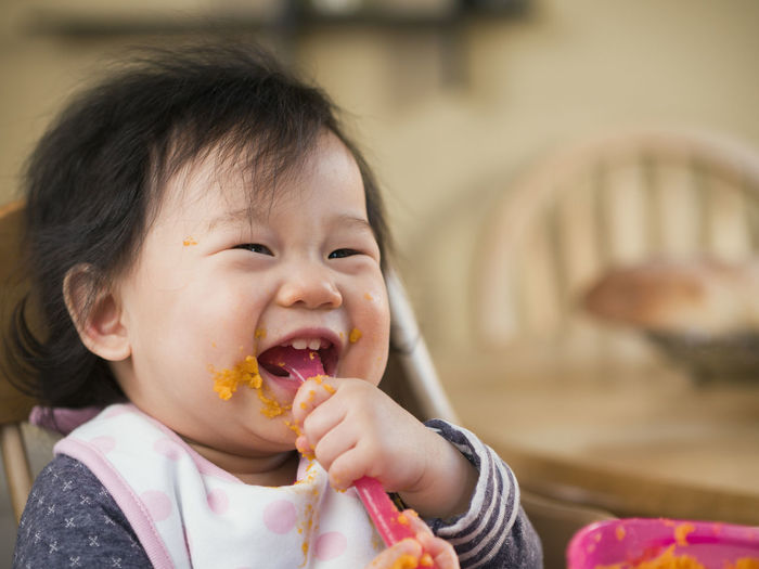 Close-up of cute baby girl eating mashed potatoes at home