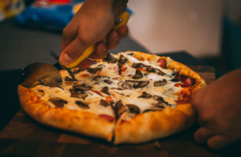 Close-up of hand holding pizza