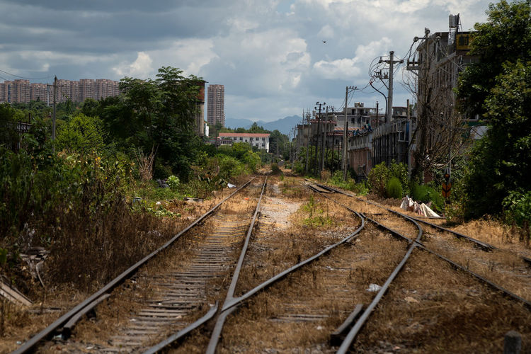 Railroad tracks by buildings in city against sky