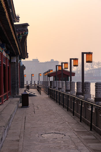 Street amidst buildings against sky during sunset