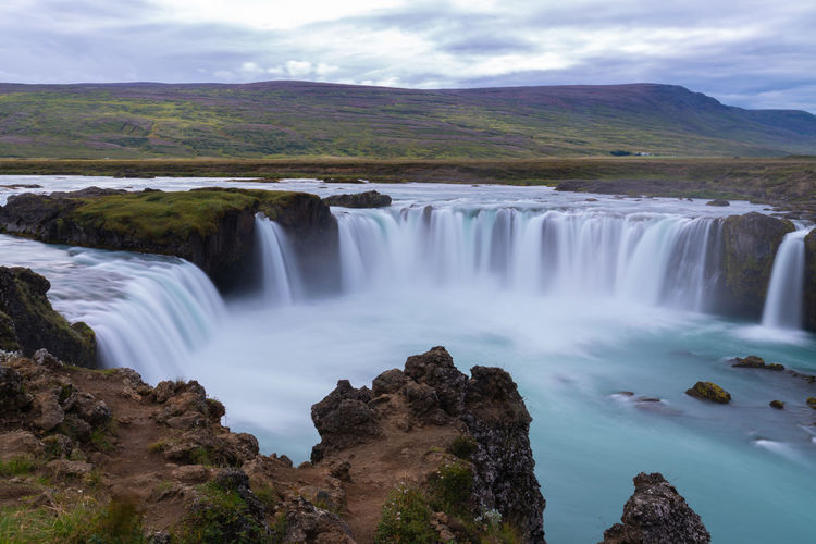 Scenic view of waterfall against sky - godafoss