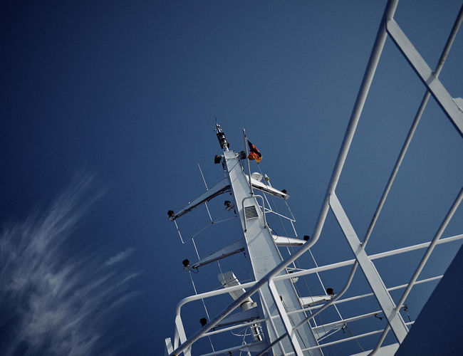 Low angle view of radar on boat against blue sky