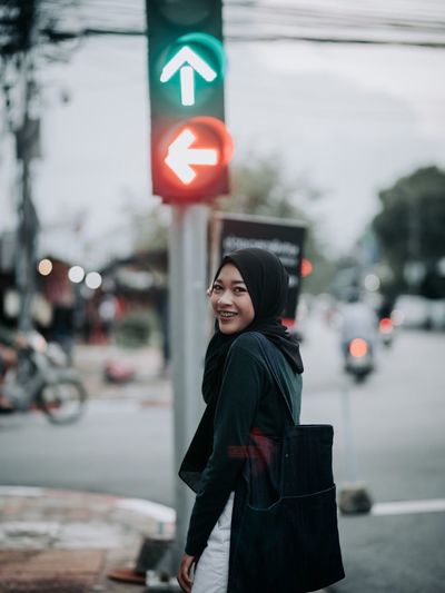 Portrait of smiling woman standing on road in city