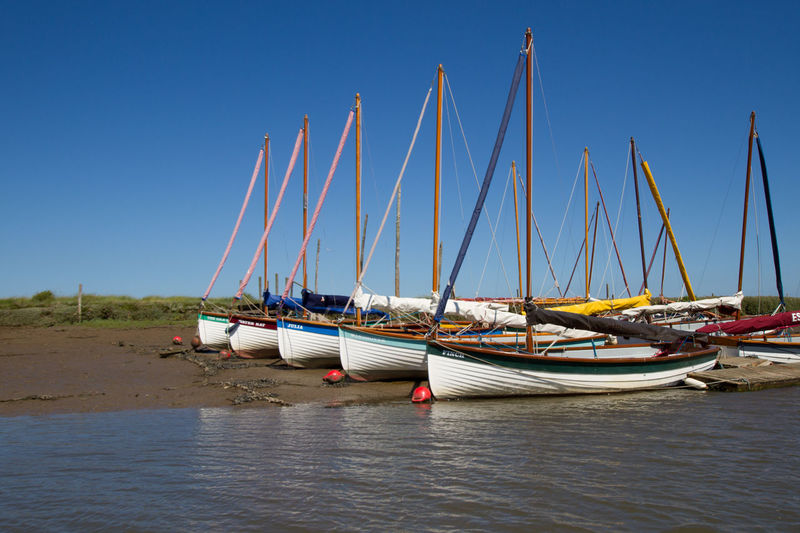 Ship moored on beach against clear blue sky