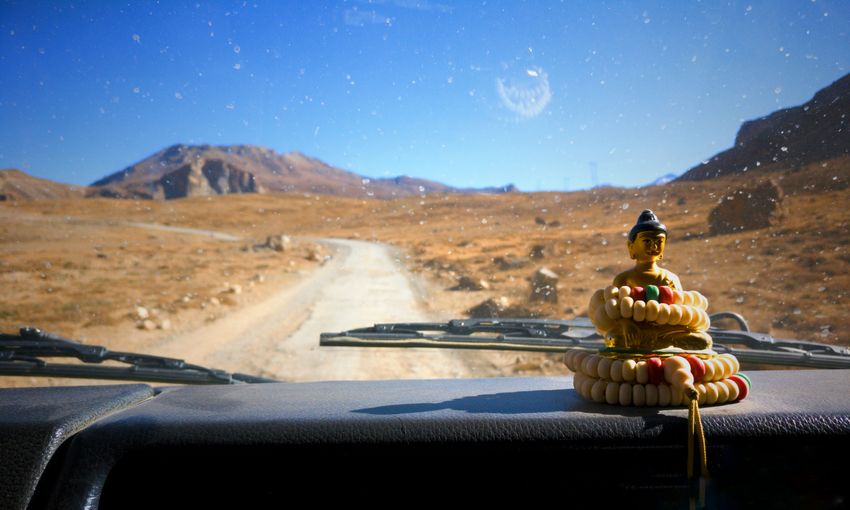 Close-up of buddha souvenir on car dashboard in desert against clear sky