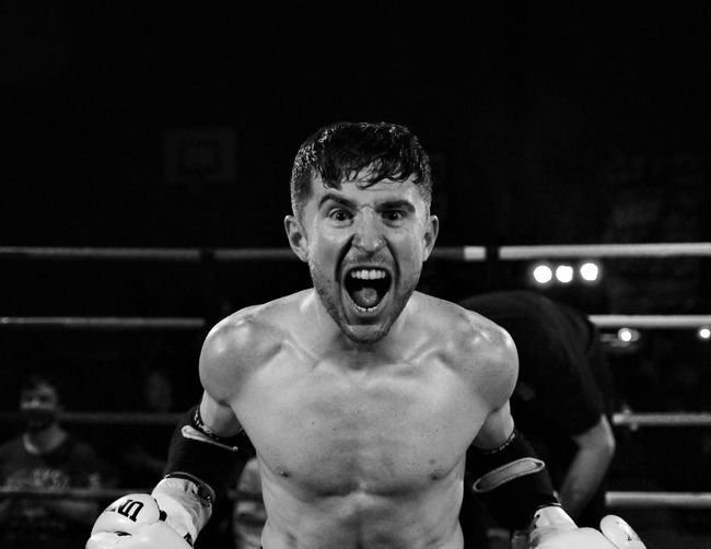 Portrait of shirtless boxer shouting while standing in boxing ring