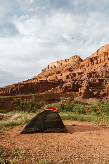 Black tent without rain fly set up beneath red rocks near moab utah