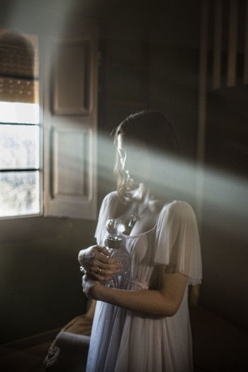 Young woman drinking glass window at home