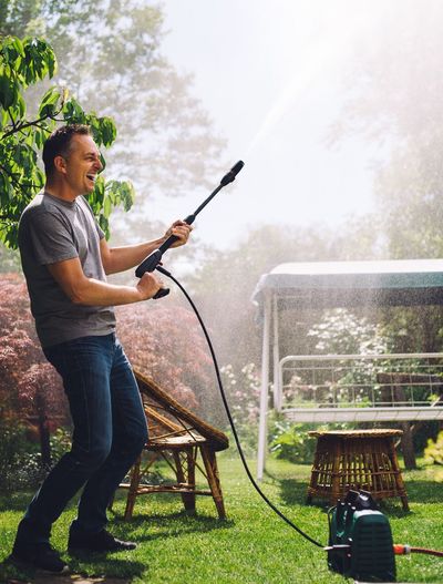Cheerful man with garden hose at back yard