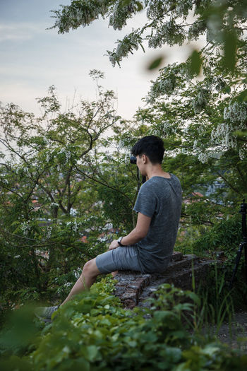 Side view of young man sitting in forest
