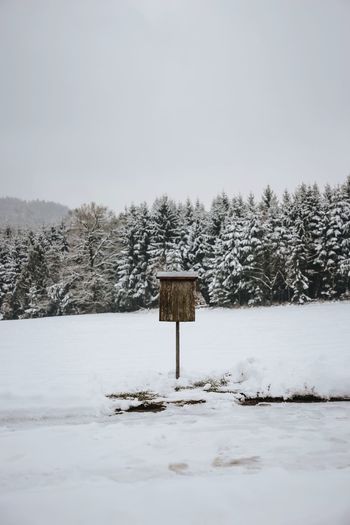 Mailbox amidst snow covered field against sky