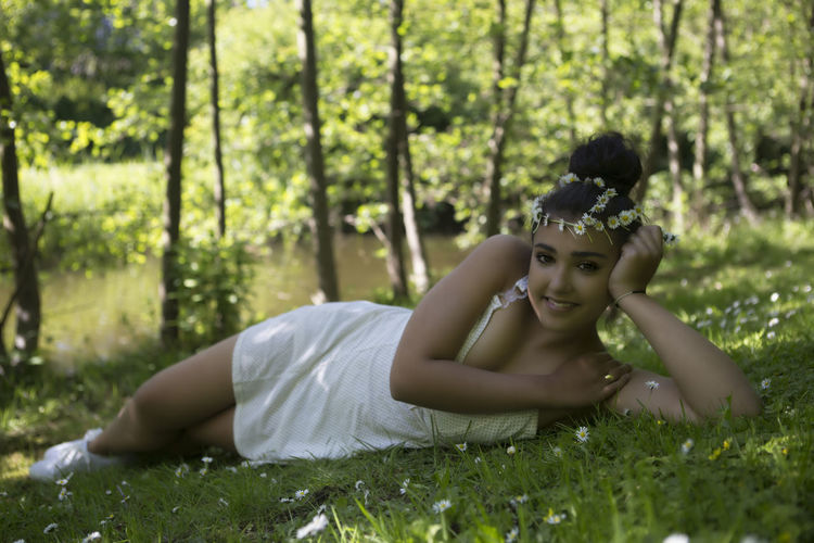 Portrait of girl wearing flowers while lying on grass