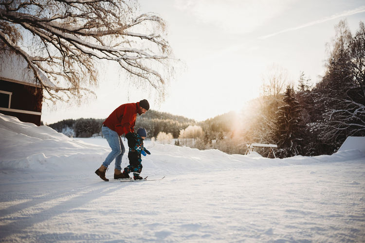 Dad teaching son to cross country ski in farm winter wonderland norway
