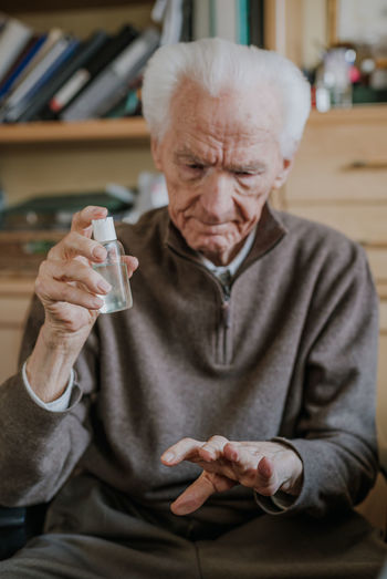 Senior man using hand sanitizer at home