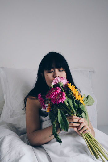 Naked woman with bouquet relaxing on bed at home