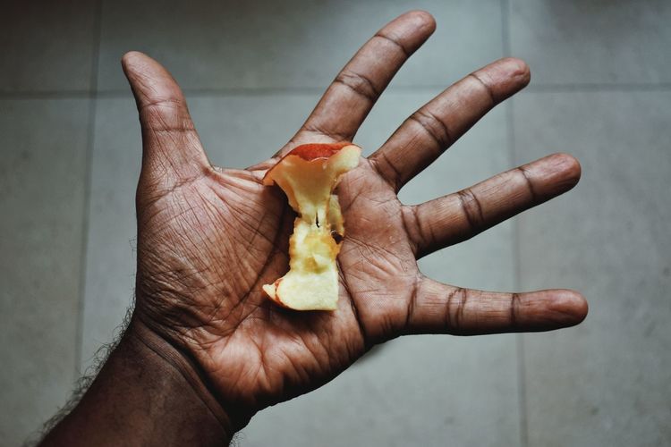 Cropped hand holding apple over floor