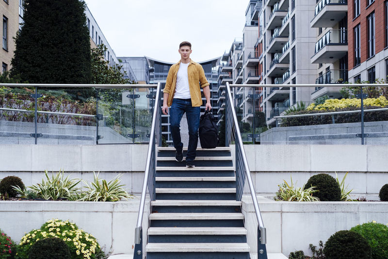 Young man with bag moving down steps